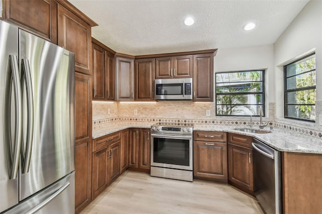 kitchen featuring light stone counters, stainless steel appliances, sink, and tasteful backsplash