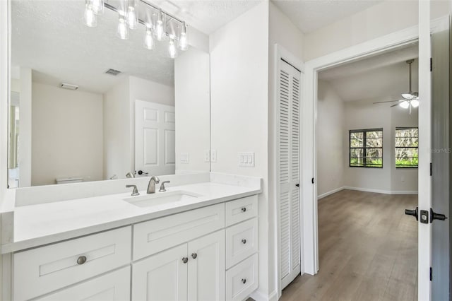 bathroom featuring vanity, hardwood / wood-style floors, ceiling fan, and a textured ceiling