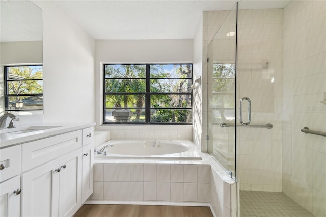 bathroom with vanity, independent shower and bath, hardwood / wood-style floors, and a wealth of natural light