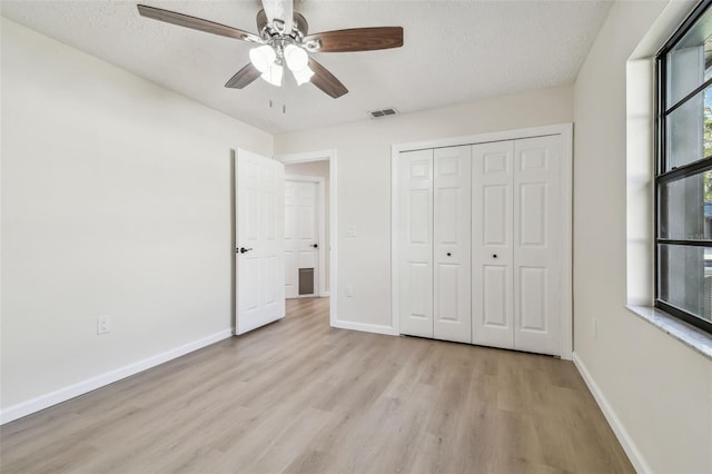 unfurnished bedroom featuring ceiling fan, light hardwood / wood-style flooring, a closet, and a textured ceiling