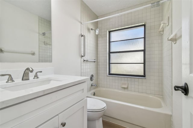 full bathroom with vanity, tiled shower / bath combo, a textured ceiling, and toilet