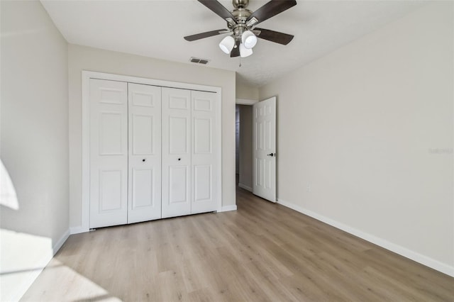 unfurnished bedroom with ceiling fan, light wood-type flooring, and a closet