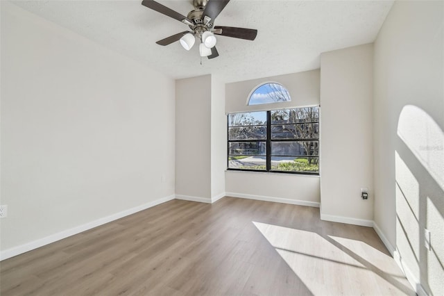 unfurnished room with ceiling fan, a textured ceiling, and light wood-type flooring