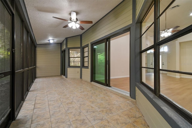 unfurnished sunroom featuring ceiling fan