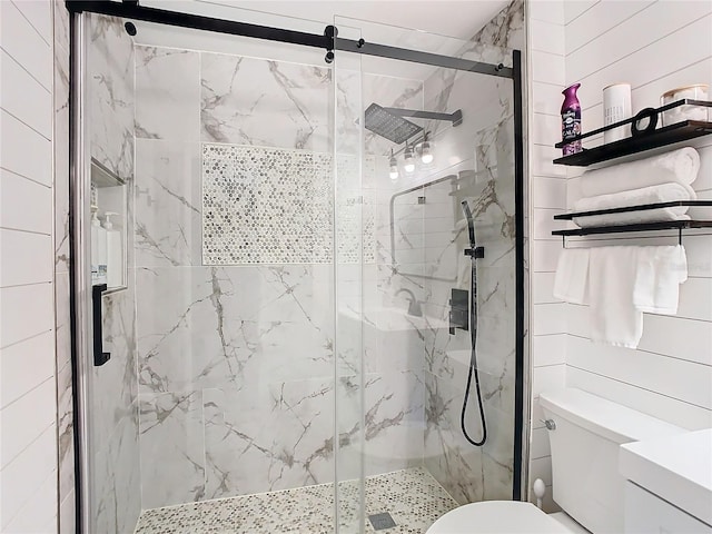 bathroom featuring a shower with door and toilet