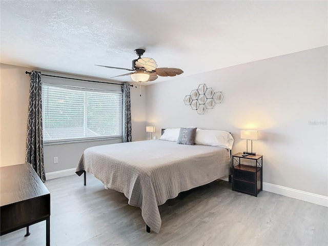 bedroom with hardwood / wood-style flooring, a textured ceiling, and ceiling fan