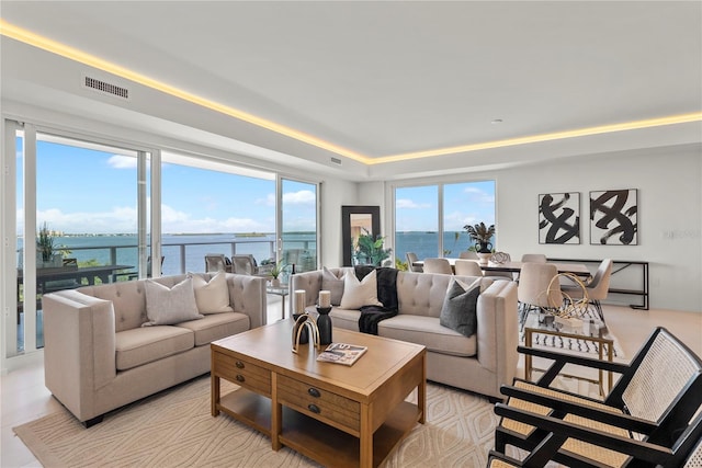 living room with a tray ceiling and a water view