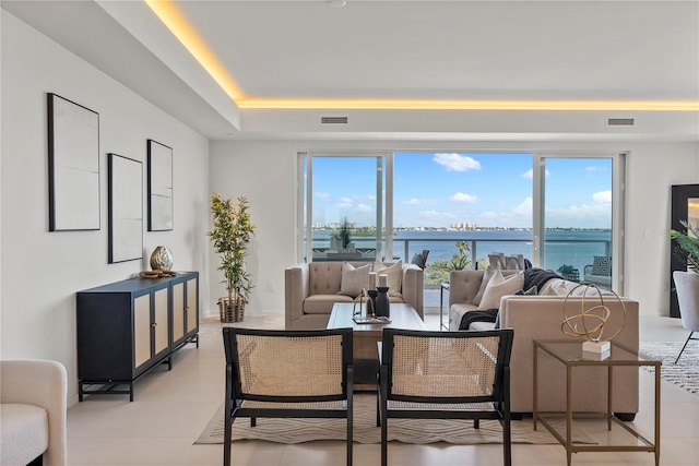 living room with a tray ceiling and a water view