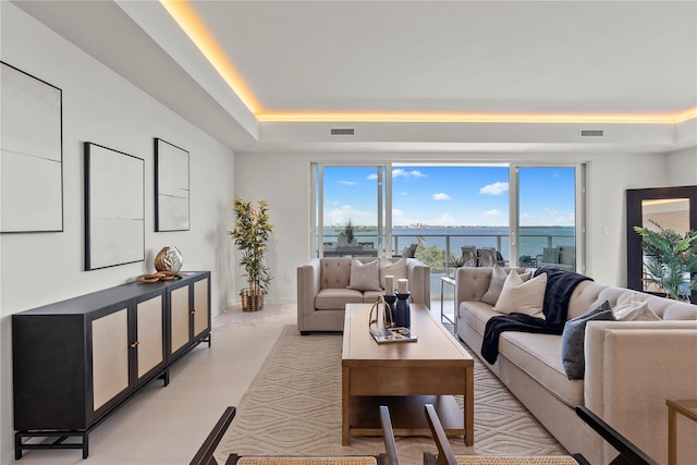 living room featuring a tray ceiling and a water view