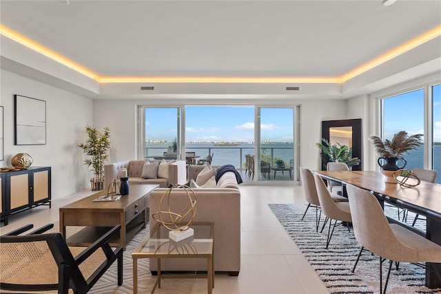 living room with light tile patterned flooring, a raised ceiling, and a water view