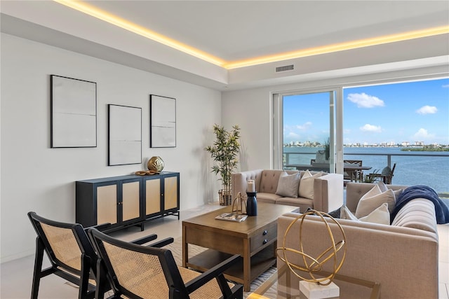 living room with a tray ceiling and a water view