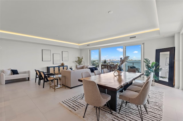 dining room with a raised ceiling and light tile patterned floors