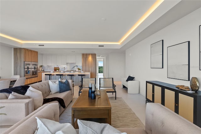 tiled living room featuring a raised ceiling