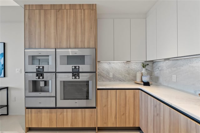 kitchen with double oven, backsplash, and white cabinets