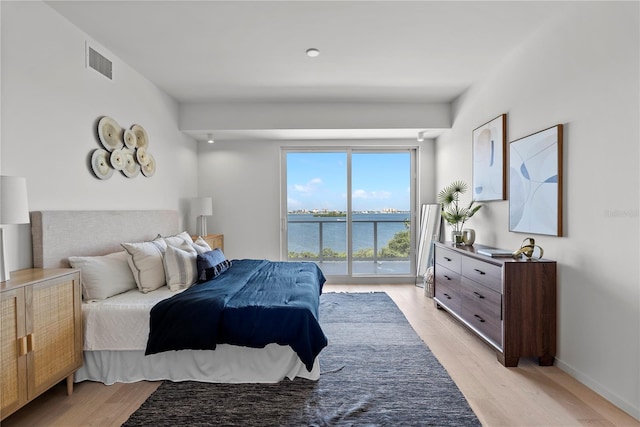 bedroom featuring a water view, access to outside, and light hardwood / wood-style floors