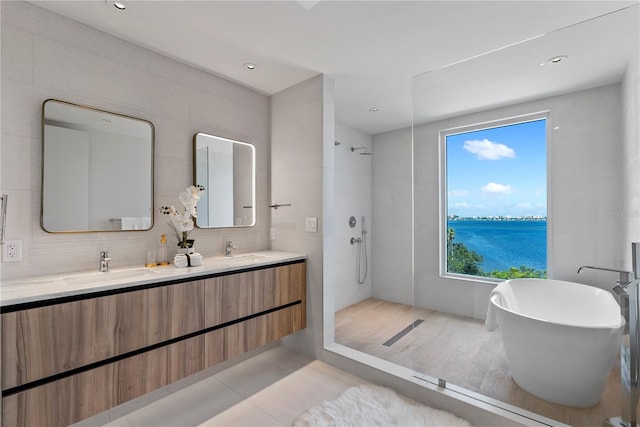 bathroom featuring tile walls, backsplash, a water view, vanity, and shower with separate bathtub