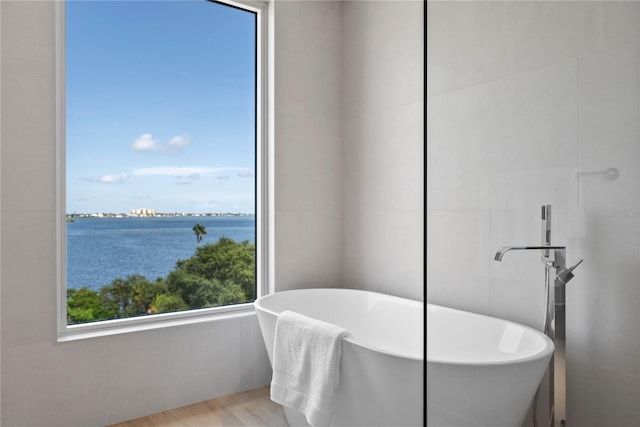 bathroom featuring a water view, a bath, and hardwood / wood-style floors