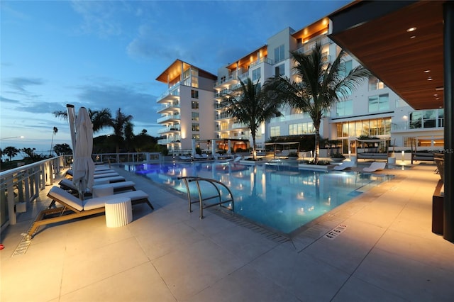 pool at dusk featuring a patio