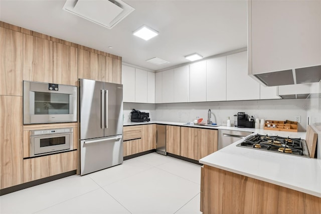 kitchen featuring light tile patterned flooring, sink, light brown cabinets, appliances with stainless steel finishes, and white cabinets