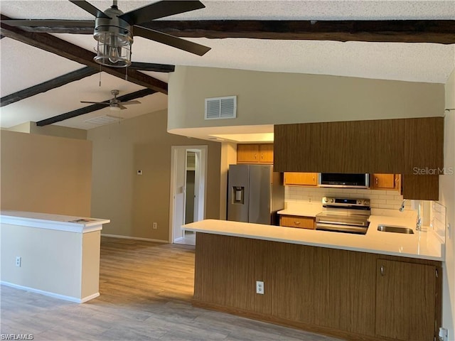 kitchen with sink, vaulted ceiling with beams, tasteful backsplash, appliances with stainless steel finishes, and kitchen peninsula