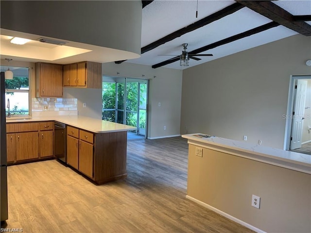 kitchen featuring plenty of natural light, kitchen peninsula, light hardwood / wood-style floors, and backsplash