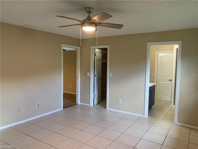 unfurnished bedroom with ceiling fan, a spacious closet, light tile patterned floors, and a textured ceiling