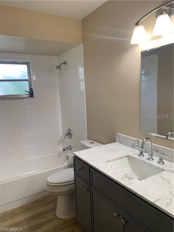 full bathroom with hardwood / wood-style flooring, vanity, toilet, and tiled shower / bath combo