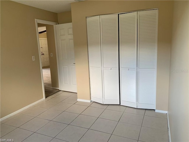 unfurnished bedroom with light tile patterned floors and a closet