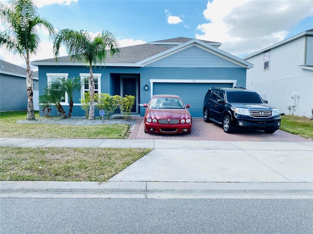 single story home with an attached garage, a shingled roof, decorative driveway, and stucco siding