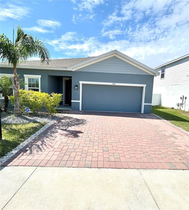 single story home featuring a garage, decorative driveway, and stucco siding