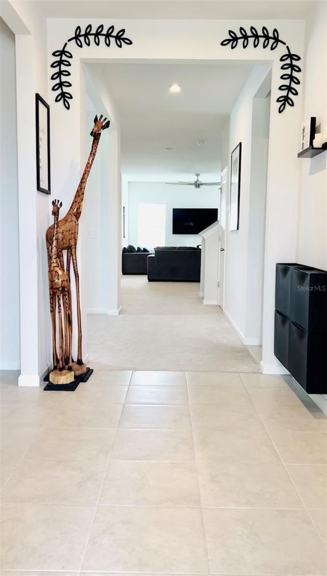 corridor featuring light tile patterned flooring and baseboards