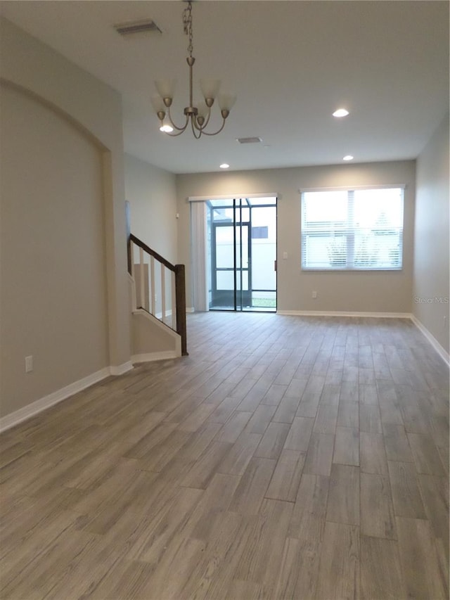 unfurnished room featuring hardwood / wood-style flooring and a chandelier