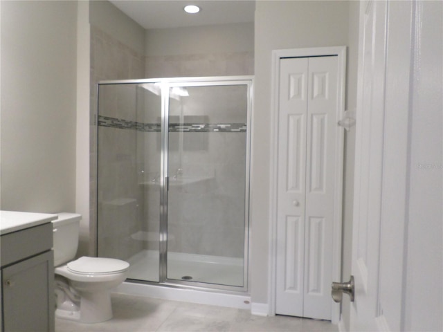 bathroom featuring an enclosed shower, vanity, tile patterned flooring, and toilet