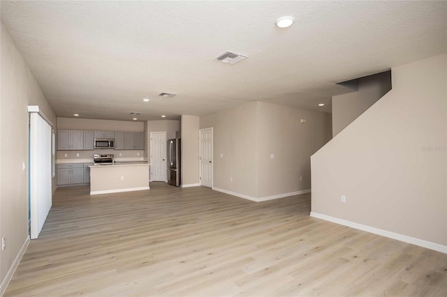 unfurnished living room featuring a textured ceiling and light hardwood / wood-style floors