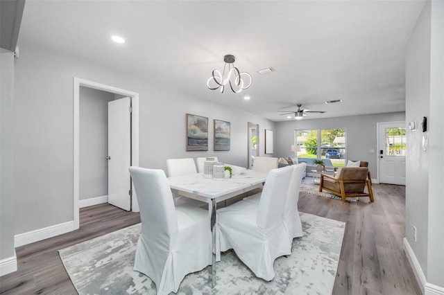 dining space with hardwood / wood-style flooring and ceiling fan with notable chandelier