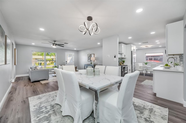 dining area with ceiling fan with notable chandelier, dark hardwood / wood-style flooring, and sink