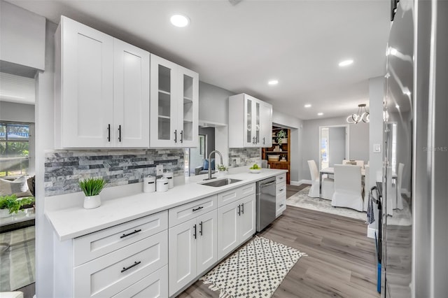 kitchen featuring appliances with stainless steel finishes, white cabinetry, sink, decorative backsplash, and hardwood / wood-style flooring