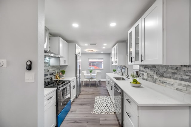 kitchen with sink, white cabinetry, tasteful backsplash, stainless steel appliances, and light hardwood / wood-style floors