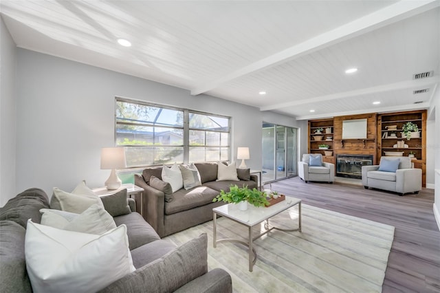 living room featuring a large fireplace, beamed ceiling, and light wood-type flooring