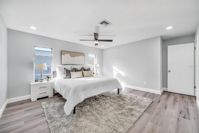 bedroom with ceiling fan, multiple windows, and light wood-type flooring