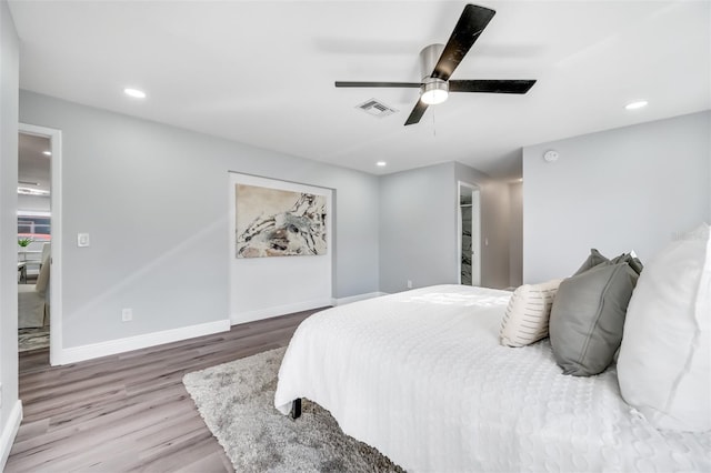 bedroom with hardwood / wood-style flooring, ceiling fan, and a spacious closet