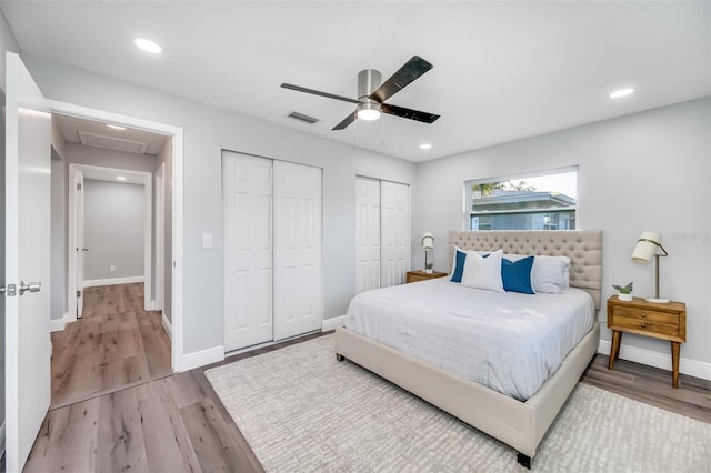 bedroom featuring ceiling fan, wood-type flooring, and two closets