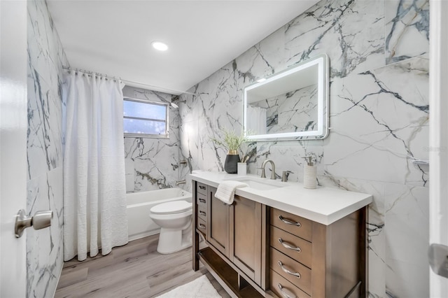 full bathroom featuring toilet, tile walls, hardwood / wood-style flooring, vanity, and shower / bath combination with curtain