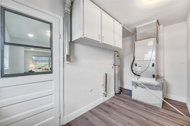 laundry area featuring cabinets, light hardwood / wood-style flooring, a textured ceiling, hookup for an electric dryer, and water heater