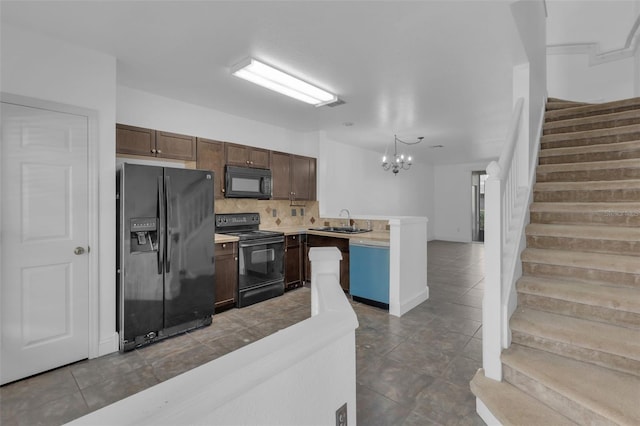 kitchen with sink, a chandelier, dark tile patterned flooring, decorative backsplash, and black appliances