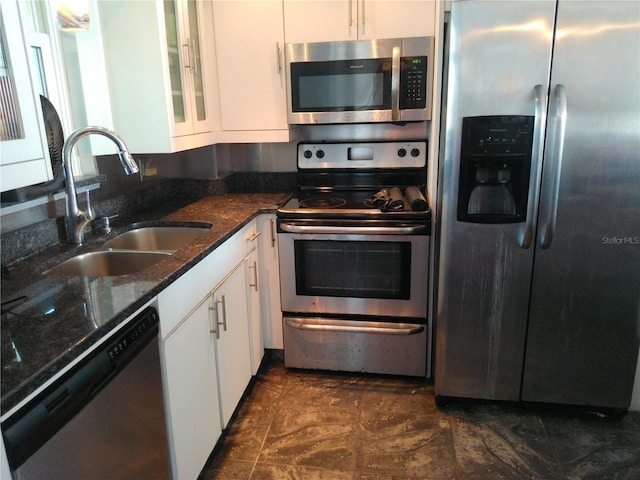 kitchen featuring white cabinetry, sink, stainless steel appliances, and dark stone countertops