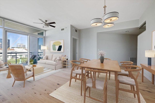 dining room featuring ceiling fan, light wood-type flooring, and a wall of windows