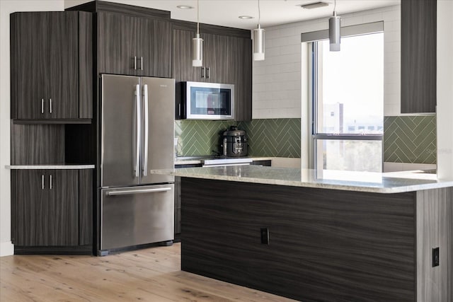 kitchen featuring light hardwood / wood-style flooring, appliances with stainless steel finishes, hanging light fixtures, dark brown cabinets, and light stone countertops