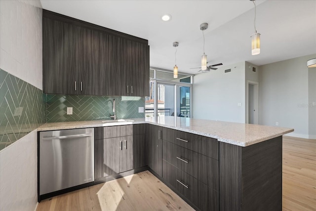 kitchen with light hardwood / wood-style flooring, backsplash, light stone counters, decorative light fixtures, and stainless steel dishwasher