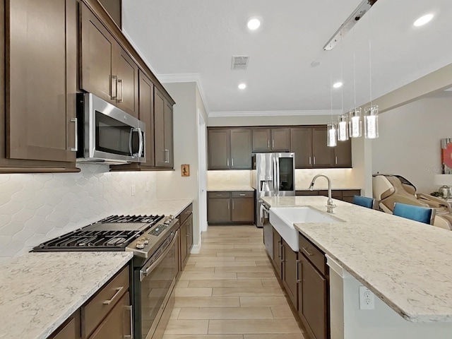 kitchen featuring sink, hanging light fixtures, light stone counters, stainless steel appliances, and dark brown cabinets